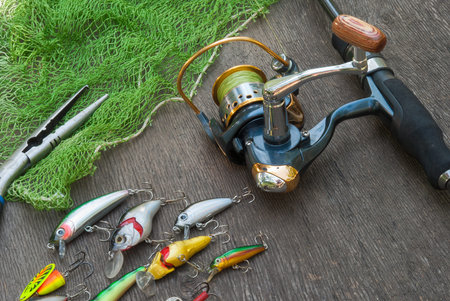 Fishing tackle - fishing spinning, hooks and lures on darken wooden background.Top view.の写真素材