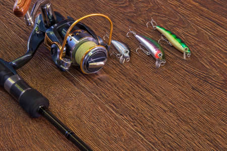 Fishing tackle - fishing spinning, hooks and lures on darken wooden background.の写真素材