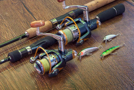 Fishing tackle - fishing spinning, hooks and lures on darken wooden background.の写真素材