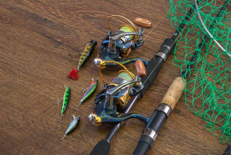 Fishing tackle - fishing spinning, hooks and lures on darken wooden background.の写真素材