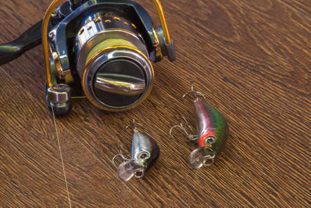 Fishing tackle - fishing spinning, hooks and lures on darken wooden background.の写真素材