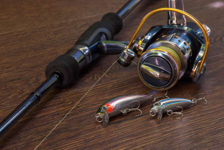 Fishing tackle - fishing spinning, hooks and lures on darken wooden background.の写真素材