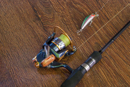 Fishing tackle - fishing spinning, hooks and lures on darken wooden background.の写真素材