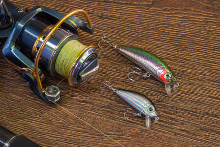 Fishing tackle - fishing spinning, hooks and lures on darken wooden background.の写真素材