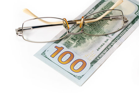 Closeup glasses on US 100 hundred dollar bill or banknote background.