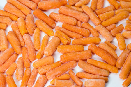 Close up of frozen baby carrots on white background.の写真素材