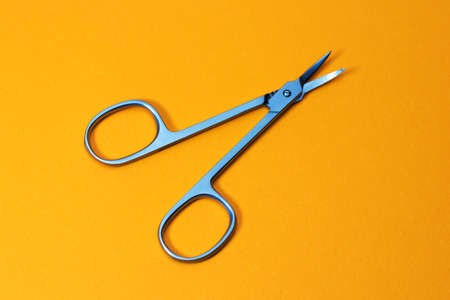 Small metal manicure scissors on yellow background.の写真素材