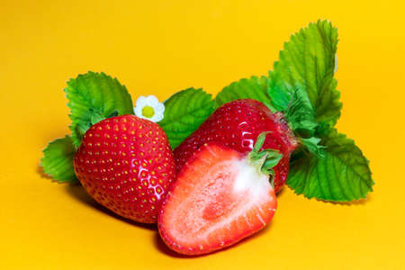 Strawberries with leaves. On a yellow backgroundの写真素材