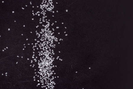 Spilled white sea salt on a black background. clear crystalline pebbles on a black background.の写真素材