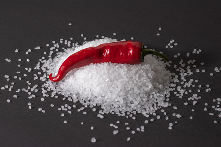 Red hot chili pepper on heap of coarse salt on darck background.の写真素材