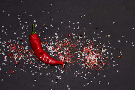 Sea salt and red hot pepper thyme and colorful peppercorns on a black.の写真素材