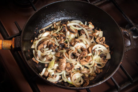 Champignons frying on the pan with onion.の写真素材
