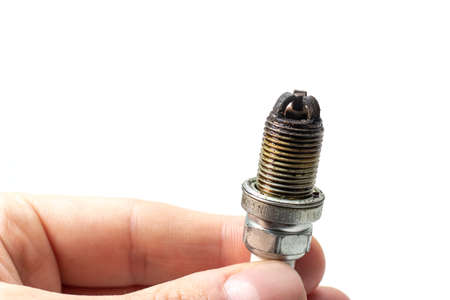 Dirty Lean Spark Plug. Auto mechanic holds an old spark plug on white background.の写真素材