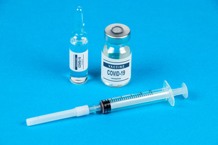 vaccination. Syringe and vaccine COVID-19. Coronavirus on blue background.