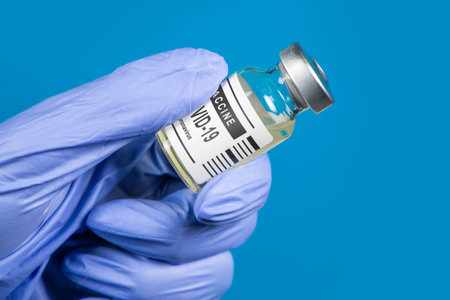 Vaccination coronavirus COVID-19. Coronavirus Vaccine in glass bottle in hand of doctor on blue...