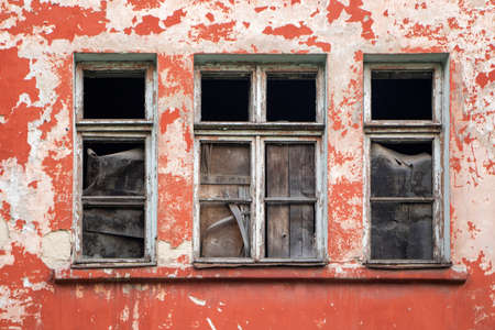 Broken old window on the red wall.の写真素材
