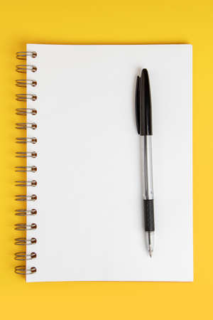 Blank note paper with pen on yellow background.の写真素材