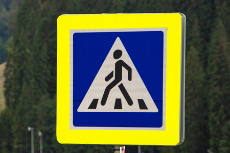 Pedestrian crossing sign on forest background.