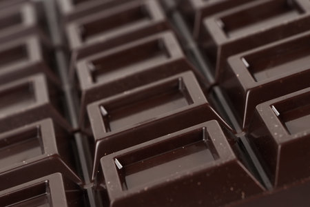 Close up a chocolate bar background. Chocolate bar cubes macro.