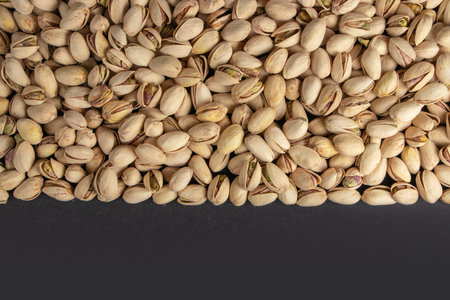 Roasted and salted pistachios in shell on dark background.