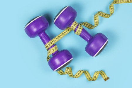 Dumbbells and measuring tape on blue background.の写真素材