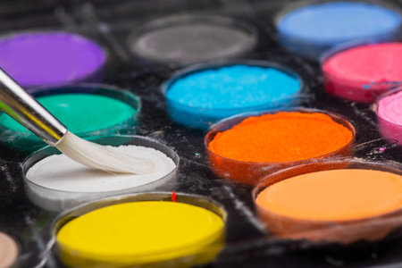 A set of colored paints with a brush in a box.の写真素材