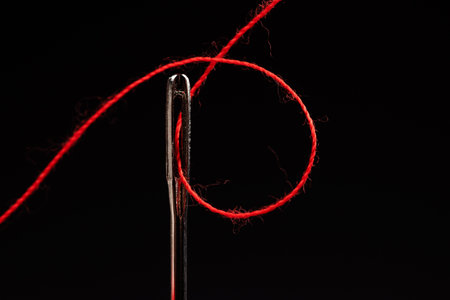 Red thread and needle on black background.の写真素材