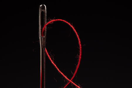 Red thread and needle on black background.の写真素材