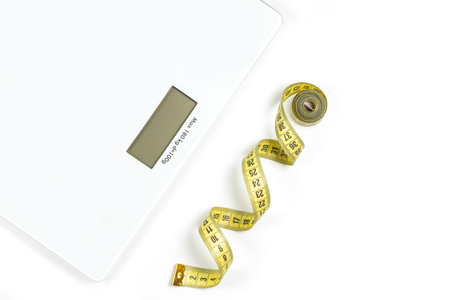 Modern scales and tape measure isolated on white, top view.