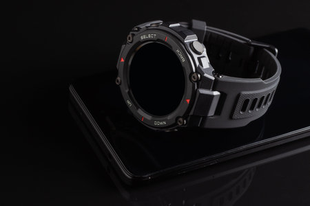 Black smart watch on the smartphone. Closeup, selective focus.