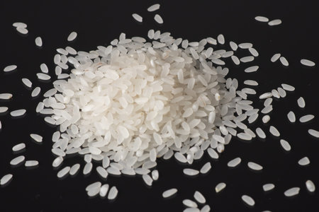 Pile white rice on black background. close up.
