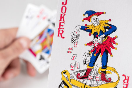 Jokerin hand on playing cards background.の写真素材