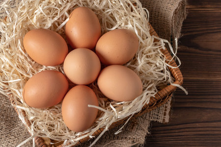 Fresh yellow eggs in the basket on wooden background.
