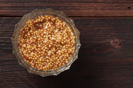 French mustard sauce in glass bowl on wooden background.の写真素材