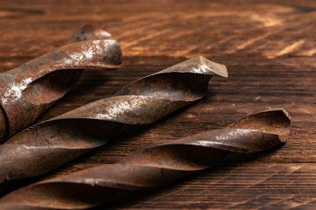 Set of metal drill bits of different sizes on wooden boards.