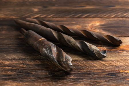 Set of metal drill bits of different sizes on wooden boards.
