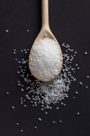 Wooden spoon with salt on a dark background.の写真素材