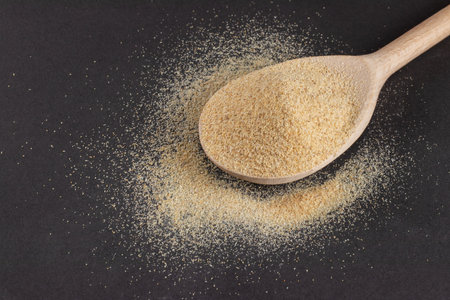 Powder garlic in a wooden spoon on a dark background.の写真素材