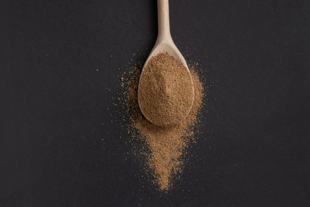 Wooden spoon with powdered coriander on dark background.の写真素材