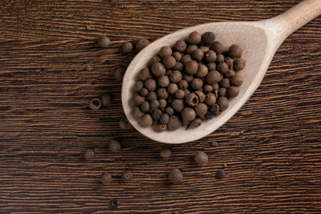 Allspice, pimento spice, Jamaican pepper in wooden spoon wooden background.の写真素材