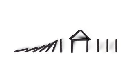 Black Domino on white background. Falling dominoes on the house. Domino effect, Hobbies and entertainment.の写真素材