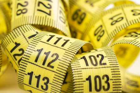 Yellow curved measuring tape close up.の写真素材