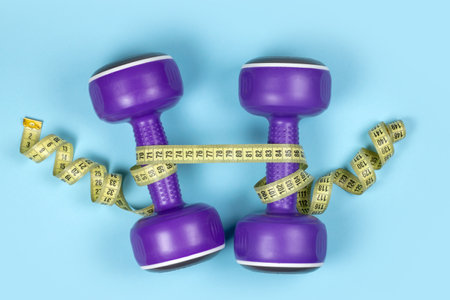 Dumbbells and measuring tape on blue background.の写真素材
