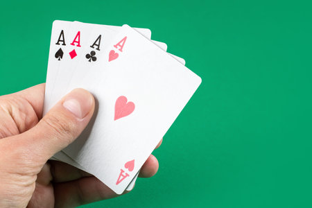 Playing cards in hand on green background.