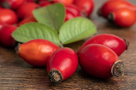Rose hips with leaves on wooden background. close up.の写真素材