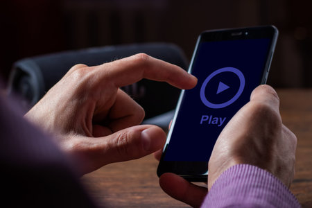 Man holding smartphone and portable music speaker on blurred background.の写真素材