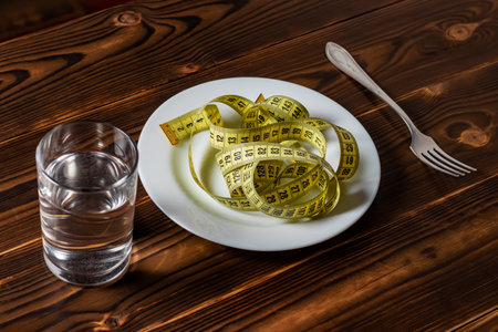 diet concept. Empty plate with measuring tape, fork and glass with water. Healthy food, weight lossの写真素材