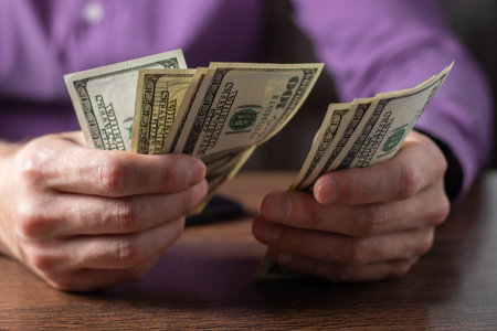 a man holds a stack of hundred-dollar bills in his hands close-up