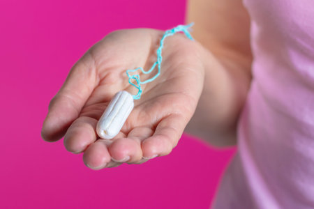 Young woman holding menstruation tampon in hand - women's menstrual cramps. Menstruation, means of protection..の写真素材