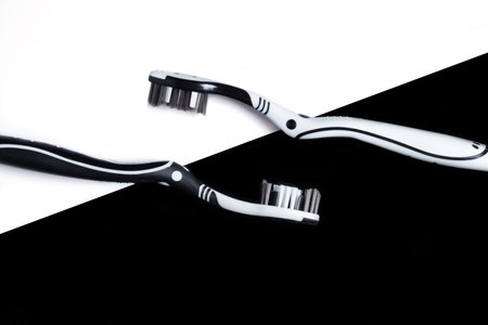 Two toothbrushes on a black and white background. The concept of oral hygiene, dental care, a...
